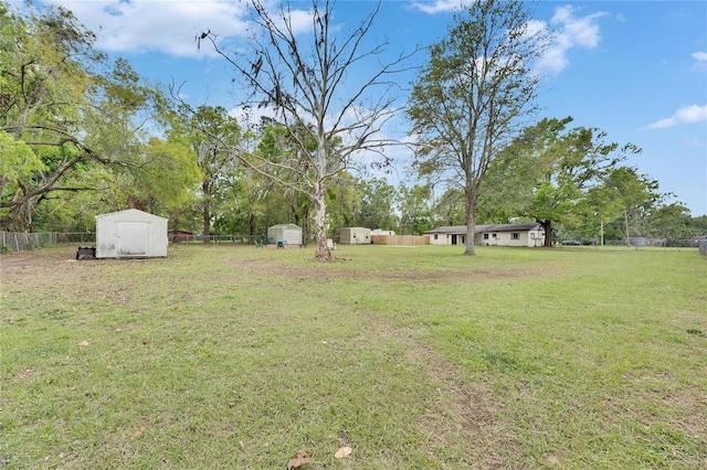 view of yard with an outbuilding, fence, and a shed