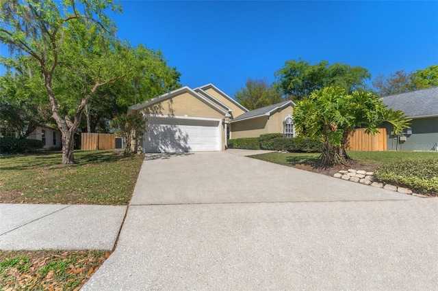 view of front of home with stucco siding, a front lawn, fence, concrete driveway, and a garage