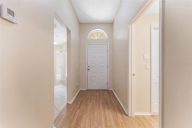 doorway to outside with light wood-style flooring and baseboards