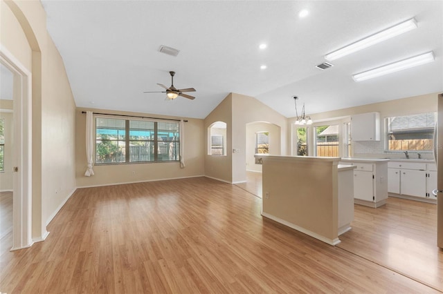 kitchen featuring arched walkways, visible vents, white cabinetry, and a kitchen island