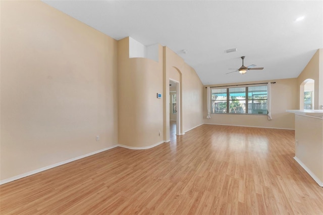 unfurnished room with baseboards, arched walkways, light wood-style flooring, and a ceiling fan