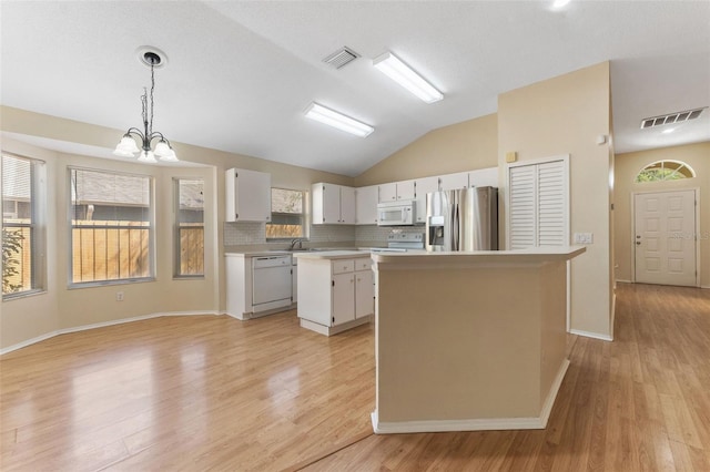 kitchen featuring white appliances, light countertops, visible vents, and a kitchen island