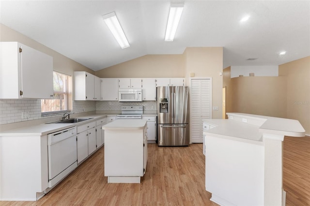 kitchen with a center island, light countertops, lofted ceiling, white appliances, and a sink