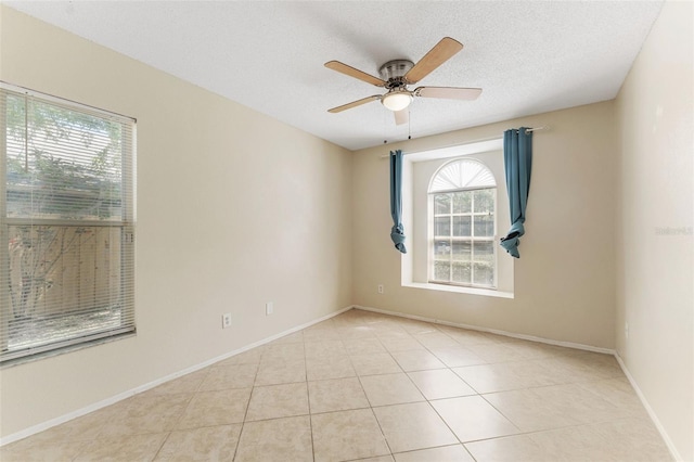 spare room featuring light tile patterned floors, baseboards, a textured ceiling, and a ceiling fan