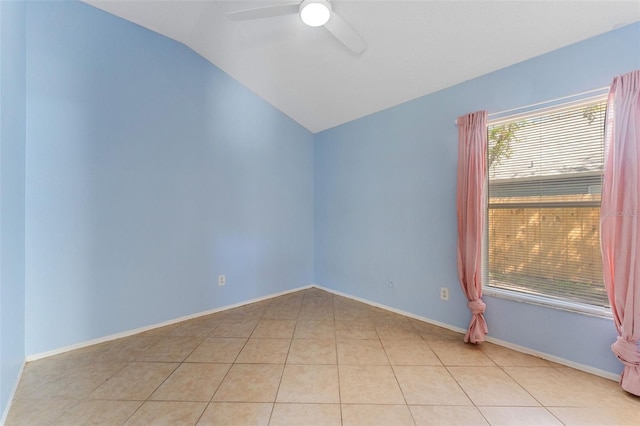 spare room with lofted ceiling, light tile patterned floors, a ceiling fan, and baseboards