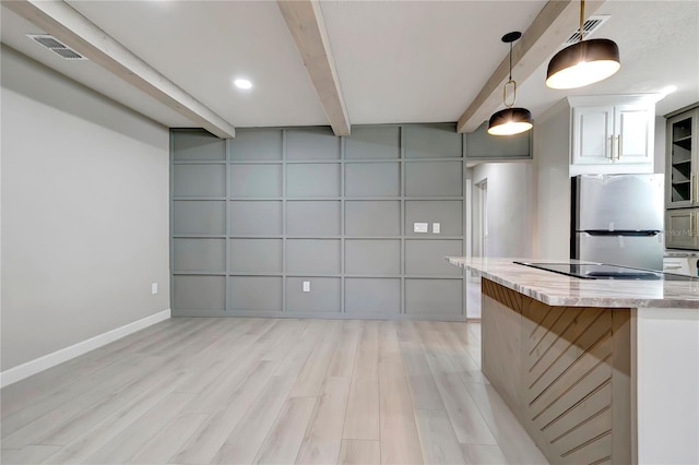 kitchen featuring light stone counters, visible vents, light wood-style flooring, freestanding refrigerator, and beamed ceiling