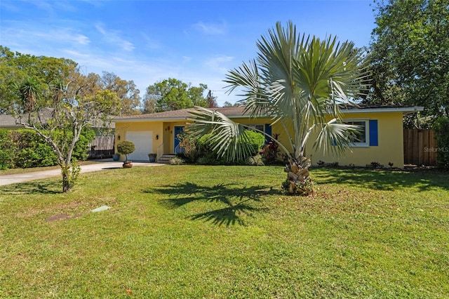 view of front of home with stucco siding, a front lawn, driveway, fence, and a garage