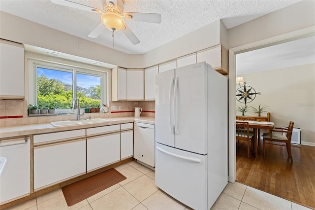 kitchen featuring a sink, white appliances, white cabinets, decorative backsplash, and tile counters