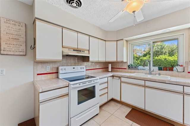 kitchen featuring visible vents, tile counters, under cabinet range hood, white electric stove, and a sink