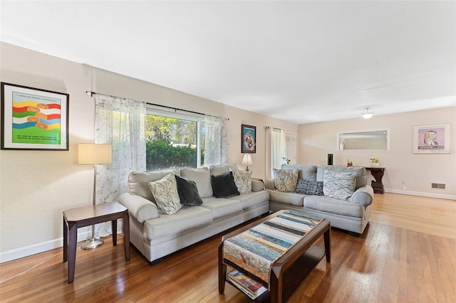 living area with visible vents, wood-type flooring, and baseboards