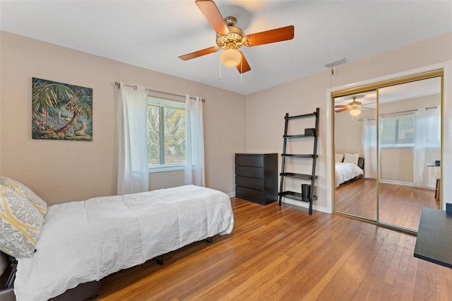 bedroom with visible vents, a closet, wood-type flooring, baseboards, and ceiling fan