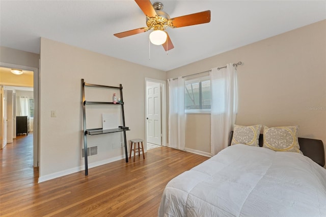 bedroom featuring visible vents, baseboards, wood finished floors, and a ceiling fan