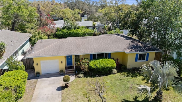 ranch-style house featuring stucco siding, a front lawn, roof with shingles, concrete driveway, and a garage