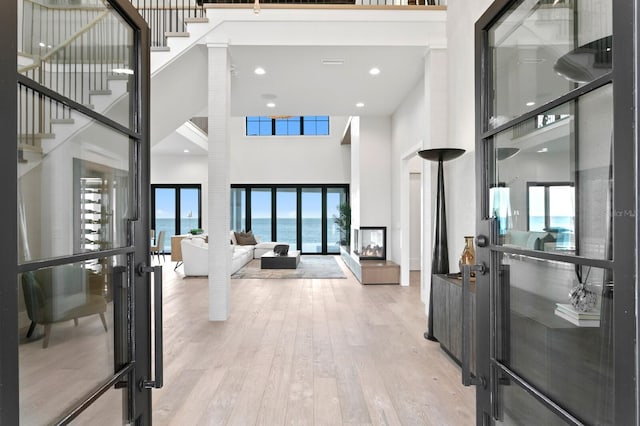 entryway with recessed lighting, stairs, light wood-type flooring, and a high ceiling