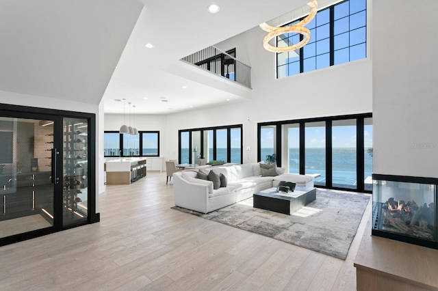 living room featuring recessed lighting, a water view, a high ceiling, and wood finished floors