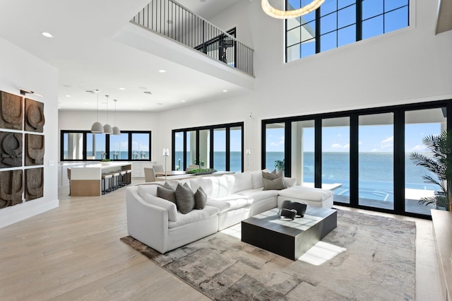 living area with recessed lighting, a water view, a healthy amount of sunlight, and light wood-style flooring