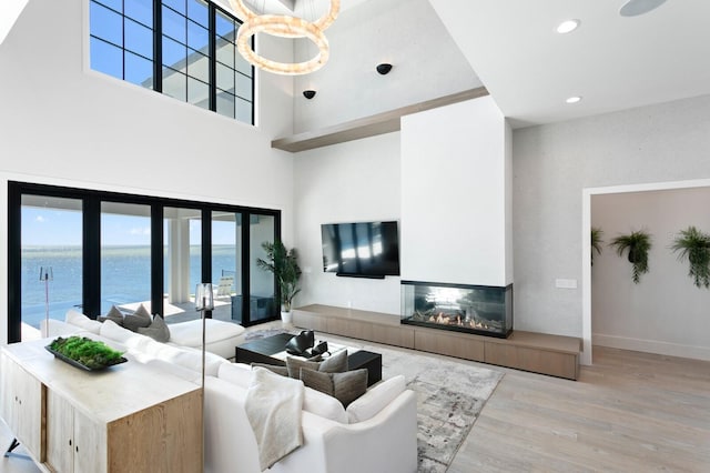 living room featuring wood finished floors, recessed lighting, a high ceiling, a fireplace, and baseboards