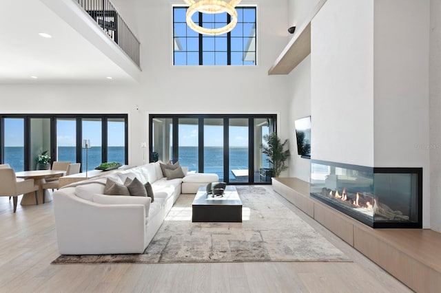 living room with wood finished floors, an inviting chandelier, a high ceiling, recessed lighting, and a tiled fireplace