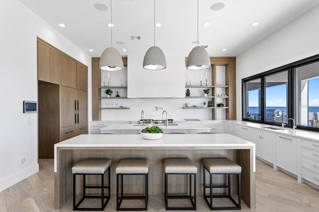 kitchen with open shelves, light wood-style floors, and a breakfast bar