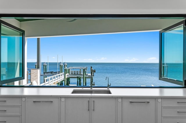 interior space featuring a sink, a water view, a healthy amount of sunlight, and light countertops