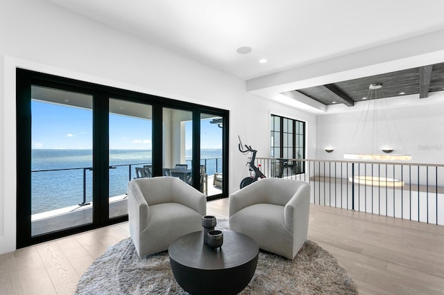 sitting room featuring recessed lighting, a water view, and wood finished floors