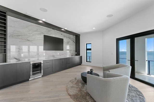 living area featuring wine cooler, light wood-style flooring, and a wealth of natural light