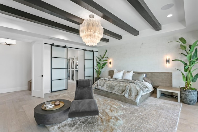 bedroom featuring a barn door, beamed ceiling, wood finished floors, and a chandelier