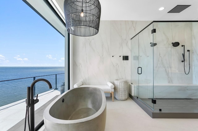 full bath featuring a freestanding tub, a water view, visible vents, recessed lighting, and a marble finish shower