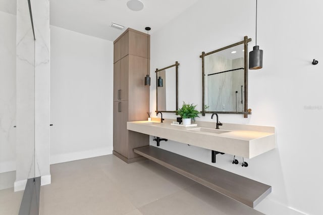 bathroom featuring baseboards, visible vents, a marble finish shower, double vanity, and a sink