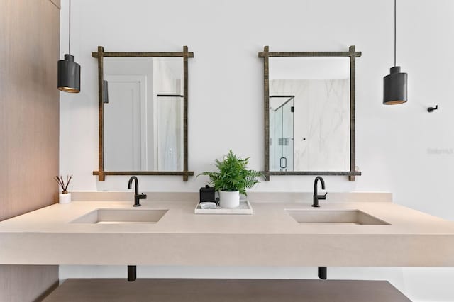 bathroom featuring double vanity, a marble finish shower, and a sink