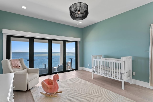 bedroom with recessed lighting, a water view, baseboards, and wood finished floors