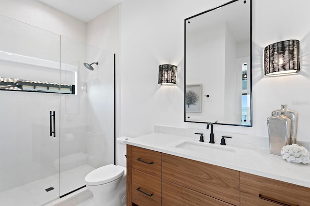 bathroom featuring a shower stall, toilet, and vanity