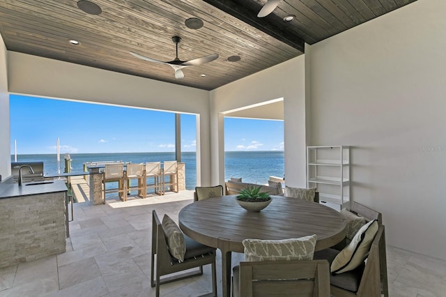 view of patio / terrace featuring a ceiling fan, area for grilling, outdoor dining area, a sink, and a water view