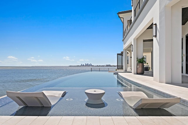 view of pool featuring an infinity pool, a patio, and a water view