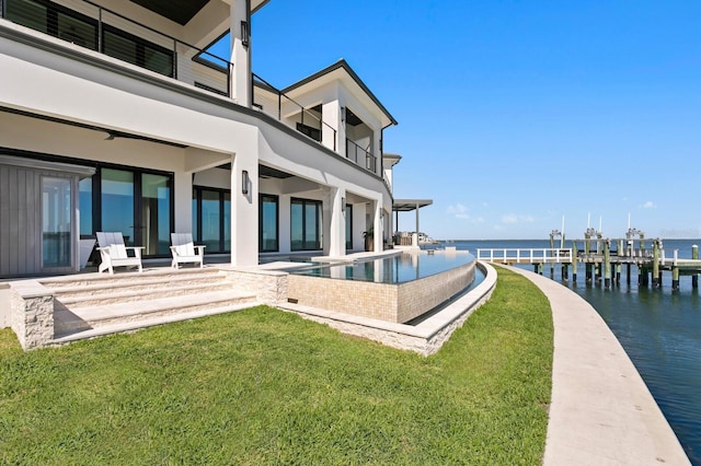 exterior space featuring a water view, a balcony, a patio, and a lawn