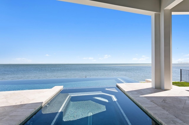 view of swimming pool with a pool with connected hot tub and a water view