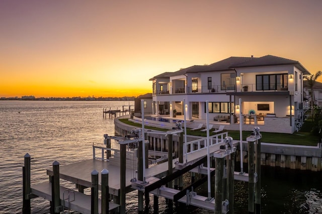 dock area with a water view, boat lift, a patio, and a balcony