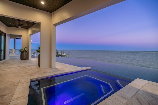 view of swimming pool featuring a water view, an in ground hot tub, and a patio