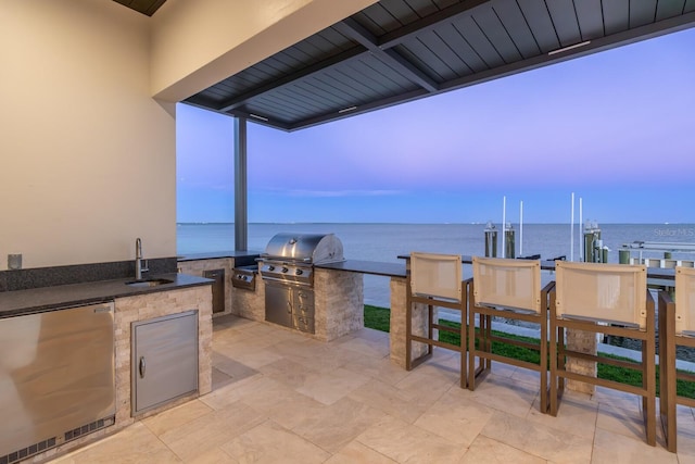 view of patio with area for grilling, a boat dock, a sink, exterior kitchen, and boat lift