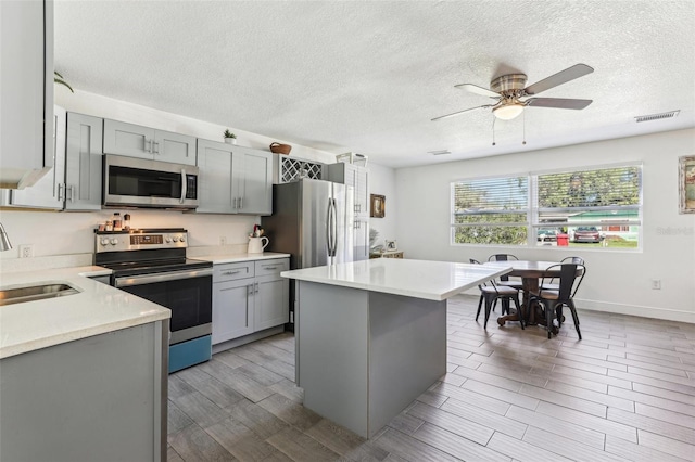 kitchen featuring visible vents, gray cabinets, a sink, stainless steel appliances, and light countertops