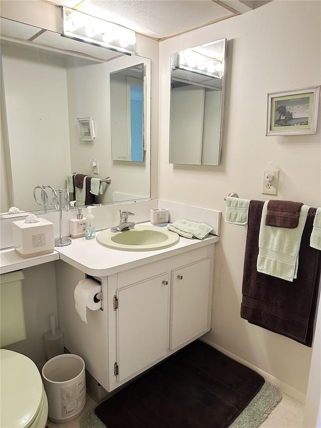 half bath featuring toilet, vanity, and baseboards