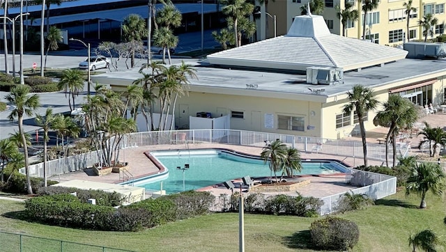 community pool with a patio, a yard, and fence