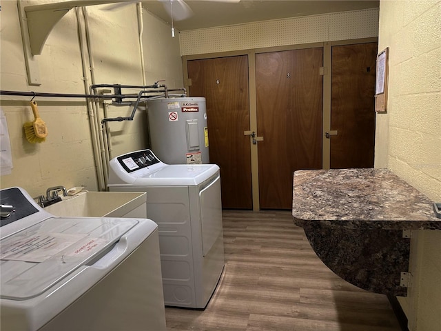 clothes washing area featuring a sink, electric water heater, wood finished floors, concrete block wall, and laundry area