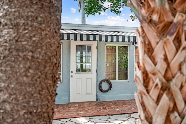 doorway to property featuring metal roof and stucco siding