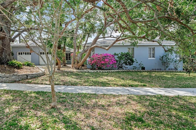 view of front of property with a garage, stucco siding, and a front lawn