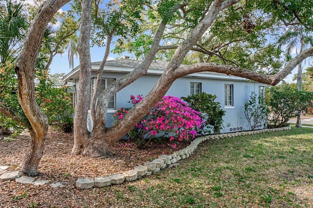 view of side of home featuring stucco siding and a yard