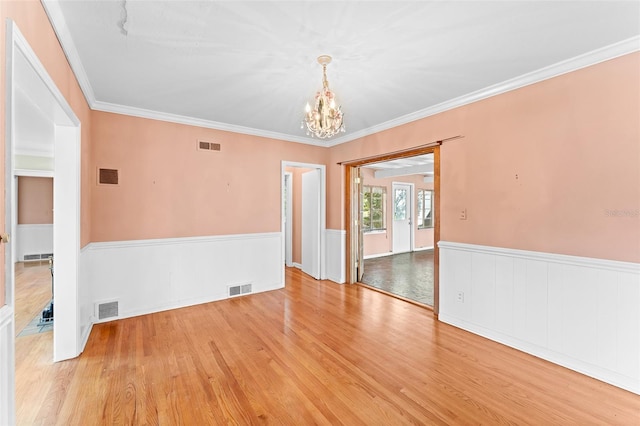 unfurnished room featuring visible vents and a wainscoted wall