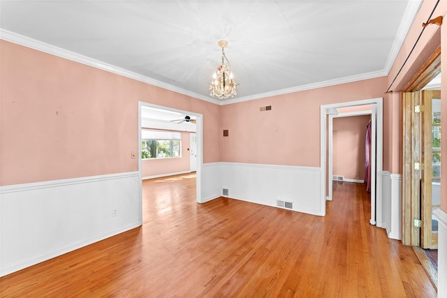 unfurnished room with visible vents, wainscoting, light wood-type flooring, and crown molding