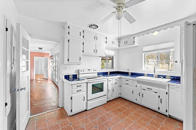 kitchen with white appliances, tile countertops, visible vents, a sink, and white cabinets