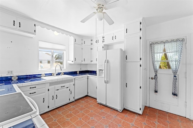 kitchen featuring white appliances, white cabinets, a wealth of natural light, and a sink